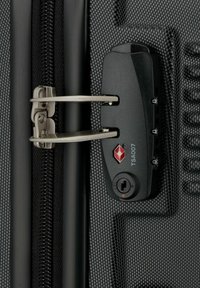 Maleta negra con cremallera y un tirador de doble cremallera plateado, además de un candado TSA. Patrón texturizado en la superficie, con un logo rojo.