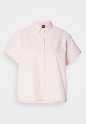 Chemise à manches courtes et boutonnée de couleur rose clair en coton. Elle présente un col classique, des boutons à l'avant et un ourlet incurvé. Texture lisse.