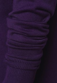 Lila gestrickter Ärmelsaum mit gerippter Textur, der an den Handgelenken gerafftes Material für eine enge Passform aufweist.