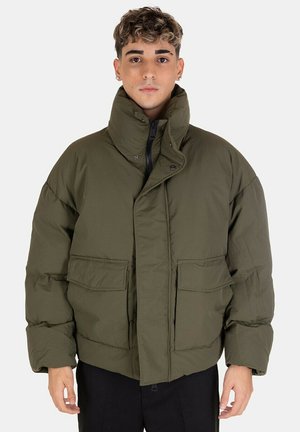 Giacca puffer verde oliva con colletto alto, chiusura frontale con zip e due grandi tasche frontali. Texture morbida e trapuntata, vestibilità ampia.