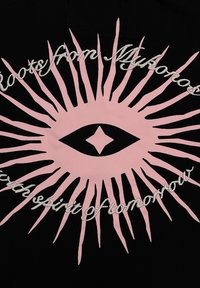 Black fabric featuring a large pink sunburst design with an eye in the center. Text reads "Roots from Mykonos" and "with spirit of tomorrow" in white.