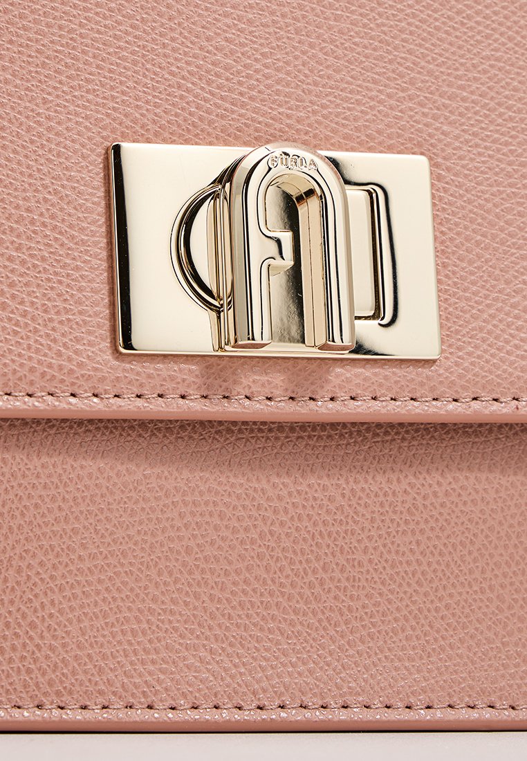 Rosa Lederhandtasche mit strukturiertem Finish, ausgestattet mit einem goldenen Verschluss in einer charakteristischen, geschwungenen Form und einer Naht entlang der Kante.