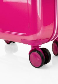 Maleta rígida de color rosa brillante con una superficie brillante, que cuenta con ruedas negras y un cierre de cremallera. Esquinas redondeadas y un diseño elegante.