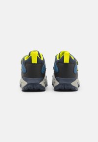 Zapatillas de trail running con parte superior de malla en azul marino y negro, acentos en amarillo neón, y suelas de goma gris con patrones de banda de rodadura texturizados.