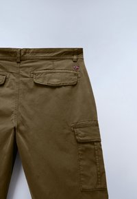 Back view of brown cargo pants showing two flap pockets and a small Norwegian flag patch near the waistband on a plain background.