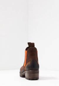 Ruske kožne gležnjače s narančastim elastičnim bočnim panelom, teksturirana površina, niski stožasti potplat i kontrastni detalj šivanja.