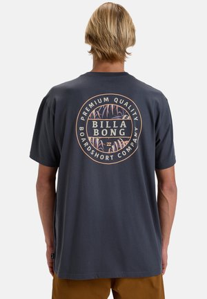 Mørkegrå t-shirt lavet af bomuld, med et rundt logo på ryggen med "BILLA BONG," flamme mønstre og en crew neck design.