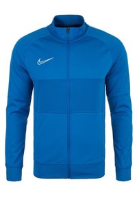 Modrá zipová bunda Nike s dlouhými rukávy, vysokým límcem a bílým logem. Má hladkou texturu a kontrastní design panelů.