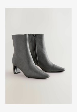 Grijze faux leren enkellaarsjes met een spitse neus, stevige zwarte hak en een zijrits. Glad oppervlak en stijlvol ontwerp.