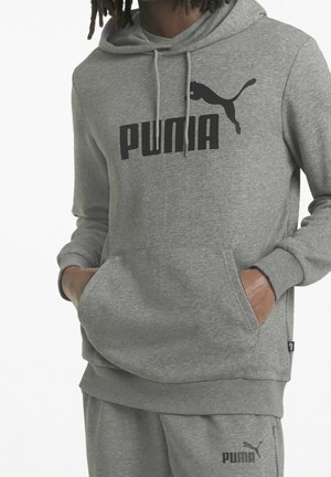 Felpa grigia con tasca frontale, con un grande logo nero "PUMA" e un silhouette di puma nera. Tessuto morbido e cappuccio con cordino regolabile.