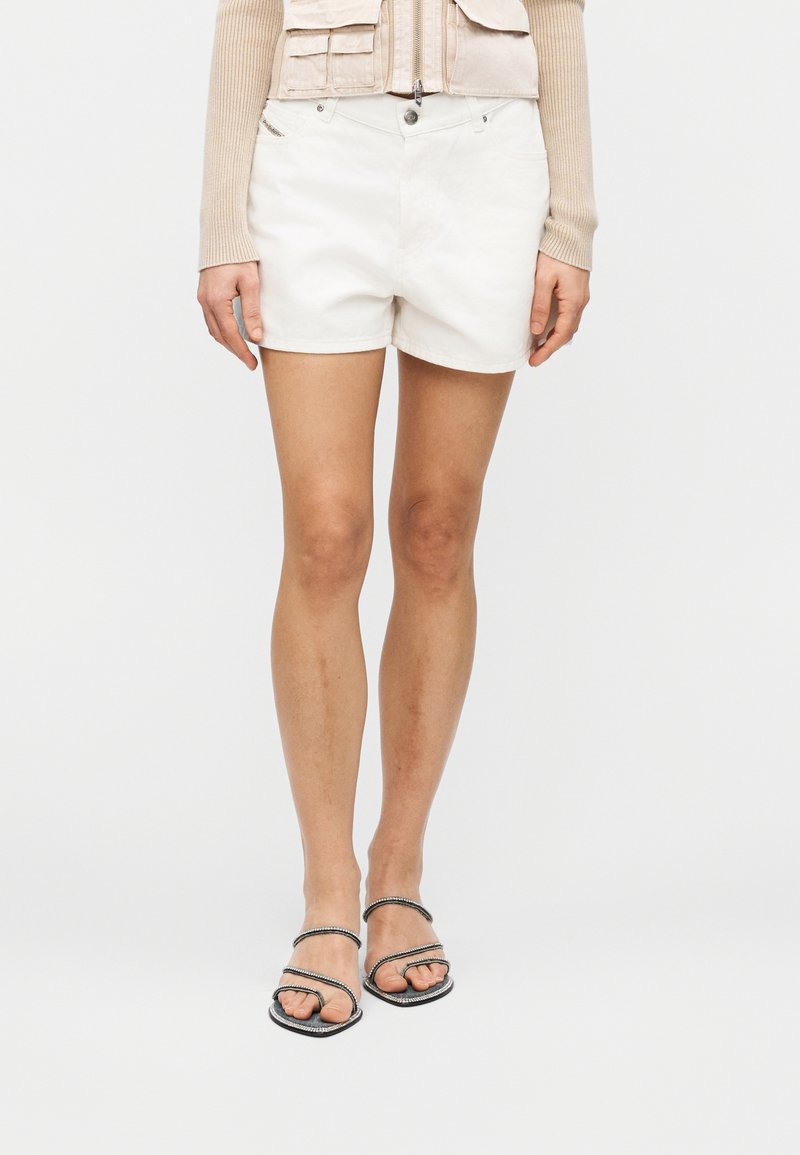 Λευκά βαμβακερά σορτς με λεία υφή, διαθέτουν δύο μπροστινές τσέπες και κλείσιμο με κουμπί. Συνδυάζονται με μαύρα σανδάλια με λουριά.