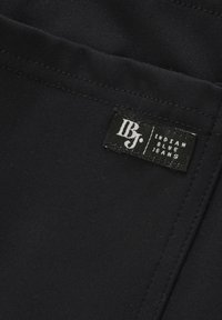 Czarne dżinsy o gładkiej fakturze z metką "Indian Blue Jeans". Szwy są widoczne wzdłuż szwów.