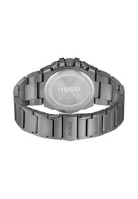 Montre en acier inoxydable avec un fini mat, cadran rond, trois boutons et un bracelet en métal avec une fermeture. Logo gravé au dos.