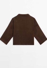 Veste courte marron foncé à manches longues, manches larges et col simple, vue de dos sur fond blanc.