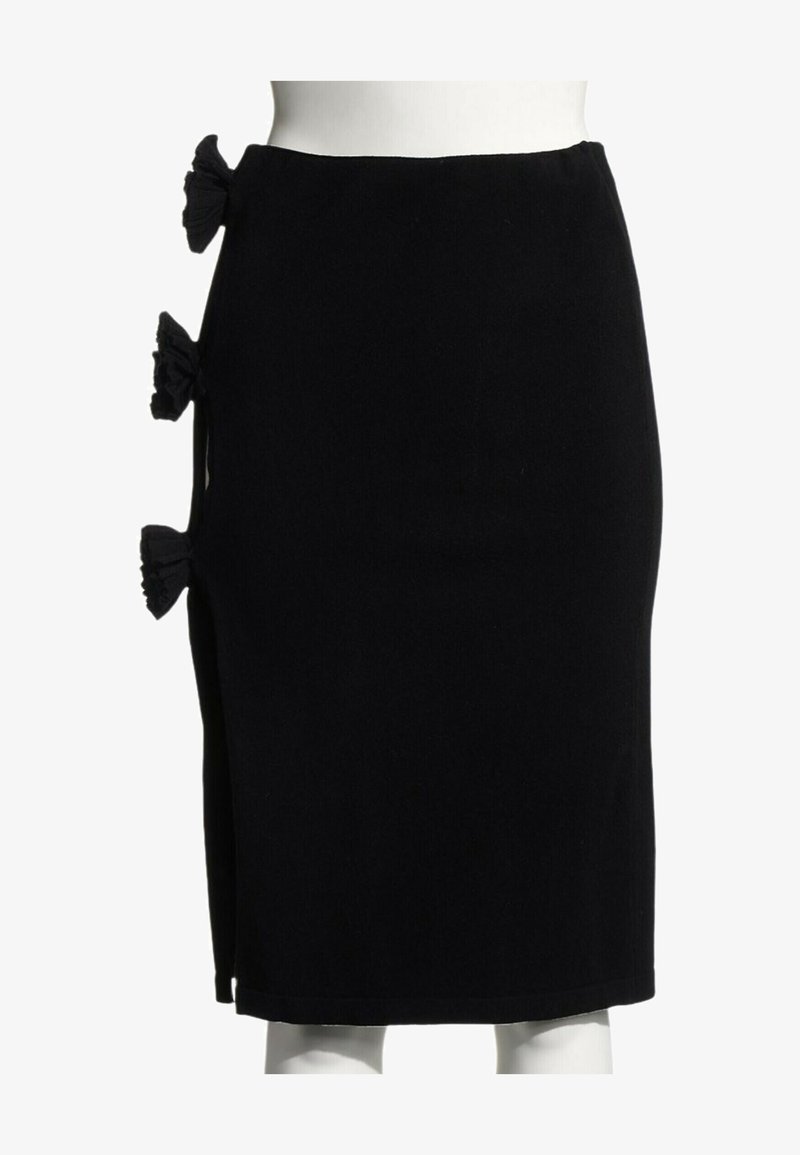 Jupe noire mi-longue avec trois nœuds en tissu le long de la fente latérale gauche, présentée sur un mannequin blanc.
