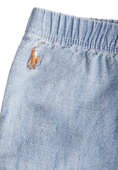 Tissu en denim bleu clair avec des détails sur la ceinture. Présente un logo de cheval brodé marron sur le côté gauche. Texture lisse.