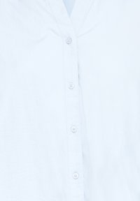 Chemise blanche boutonnée avec col, montrant la patte de boutonnage avant avec quatre boutons blancs fermés.