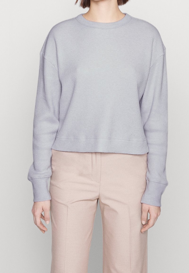 Lichtpaarse cropped sweatshirt met geribbelde textuur, ronde halslijn en relaxte pasvorm. Lange mouwen hebben contrasterende manchetten.