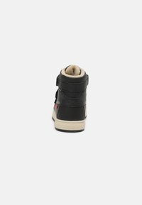 Sneaker alta nera con fodera beige, due cinturini regolabili e suola in gomma. Presenta una finitura testurizzata e un logo sulla parte posteriore del tallone.