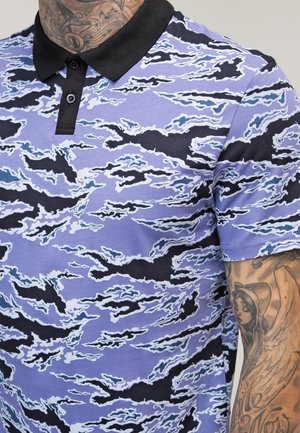 Polo shirt met een zwarte kraag met een blauw-paarse wolkenpatroon. Het materiaal lijkt zacht met een gladde textuur en heeft een getailleerd ontwerp.