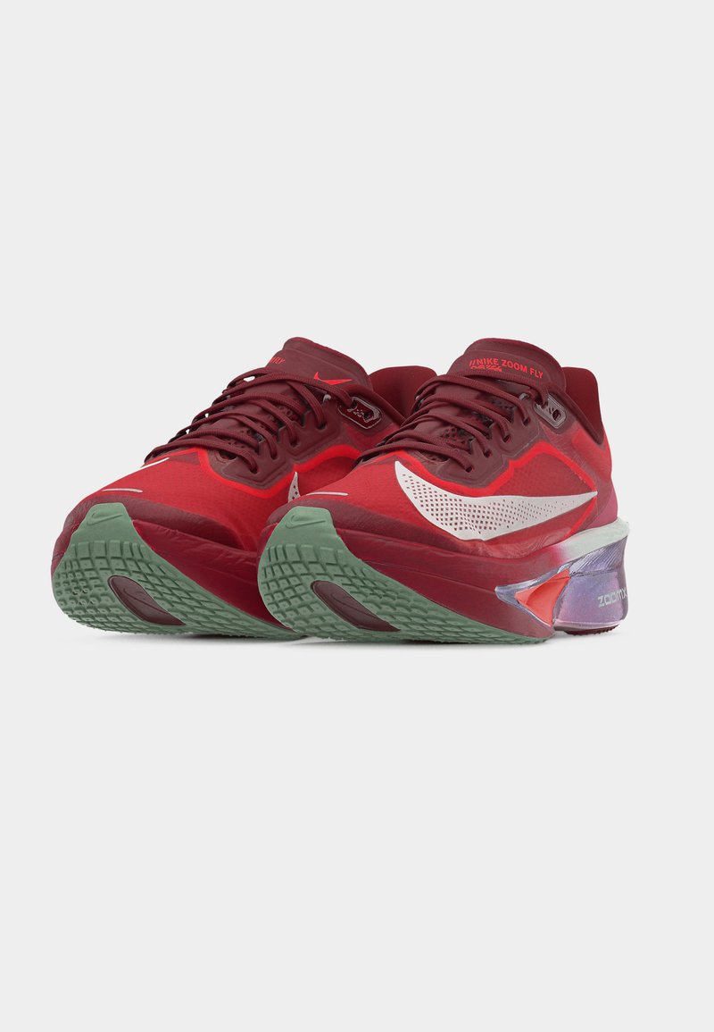 Para czerwonych i bordowych butów do biegania Nike Zoom Fly z białym logo Swoosh i zielonymi, teksturowanymi podeszwami, skierowanych do przodu na jednolitym tle.