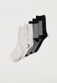 Quatre paires de chaussettes : une gris clair, deux noires unies et une noire à rayures blanches. Matières en maille douce, longueurs variées.