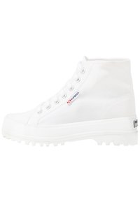 Sneaker alta in tela bianca con finitura texture, suole in gomma e punta rinforzata. Presenta fori per lacci e un logo sul lato.