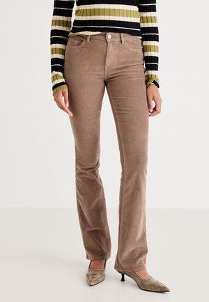 Bruine corduroy broek met wijde pijpen en verticale ribbels, vijf zakken en een knoopsluiting, gecombineerd met een zwart-groen gestreept top met lange mouwen.