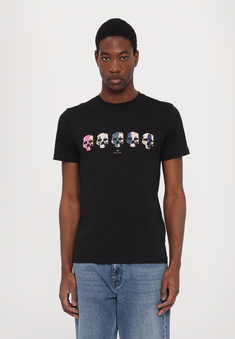 Svart bomullströja med en färgglad dödskallegrafik i rad i mitten. Kort ärm, rund halsringning och en avslappnad passform. Inga synliga logotyper.