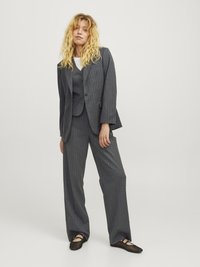 Grå pinstriped dress med en skreddersydd blazer, matchende vest og vide bukser. Teksturert stoff, minimalistisk design, kombinert med svarte fottøy.