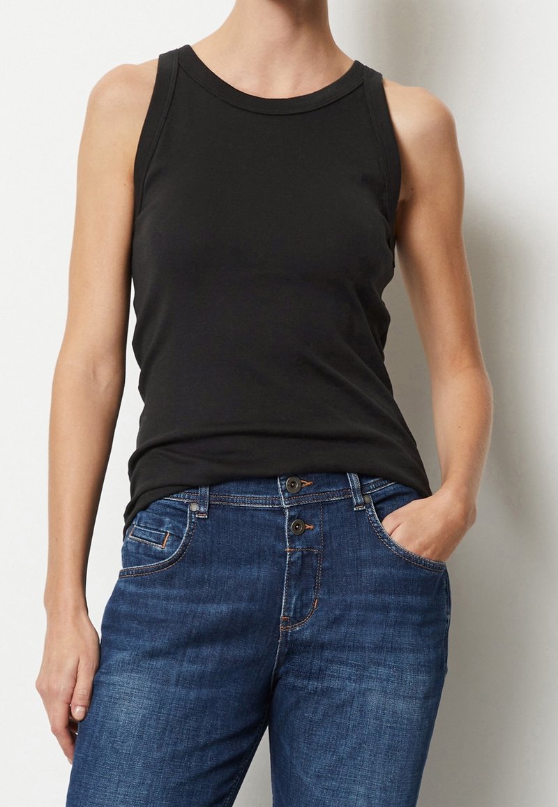Top senza maniche nero in cotone, caratterizzato da un collo rotondo e un design aderente, abbinato a jeans in denim blu con tasche e doppio bottone.