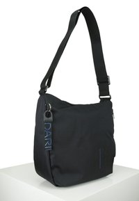 Borsa a tracolla in tessuto nero con spallaccio, dotata di chiusura con zip, dettagli del logo e una texture liscia. Design compatto e semplice.