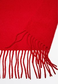 Rode wollen sjaal met franjes aan de randen. De textuur is zacht met een gladde afwerking, die warmte en comfort biedt.