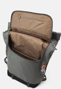 Grau farbener Stoffrucksack mit einem Reißverschluss-Hauptfach, brauner Innenausstattung und einer kleinen Außentasche. Verfügt über Metallbeschläge und verstellbare Träger.
