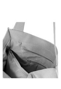 Grijze leren tote bag met een gestructureerde buitenkant. Het interieur heeft een stoffen voering en twee ritszakken voor organisatie.