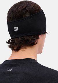 Zwarte sporthoofdband van textiel met structuur, met een rechthoekig wit logo aan de achterkant, ontworpen voor een nauwsluitende pasvorm.