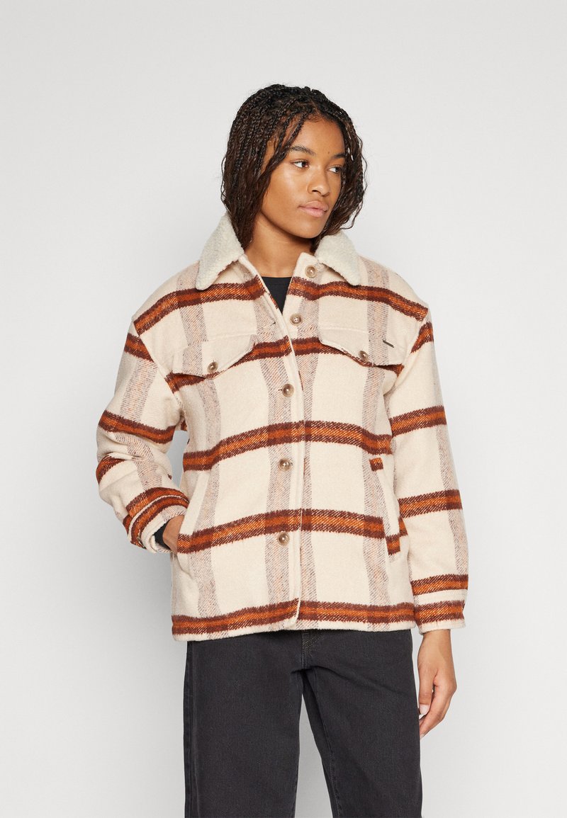 Fleecejakke med beige base og brune rutemønstre, med en shearlingkrage, snapknapper og frontlommer. Teksturert overflate.