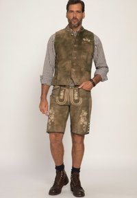 Brun mockakavaj med en rutigt skjorta, matchande bruna shorts med ornamental broderi och snörade bruna stövlar.