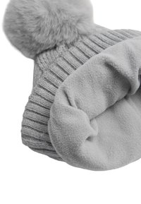Gorro de punto gris con diseño acanalado, adornado con un suave pompón de piel sintética gris. Interior forrado con una textura suave de forro polar.