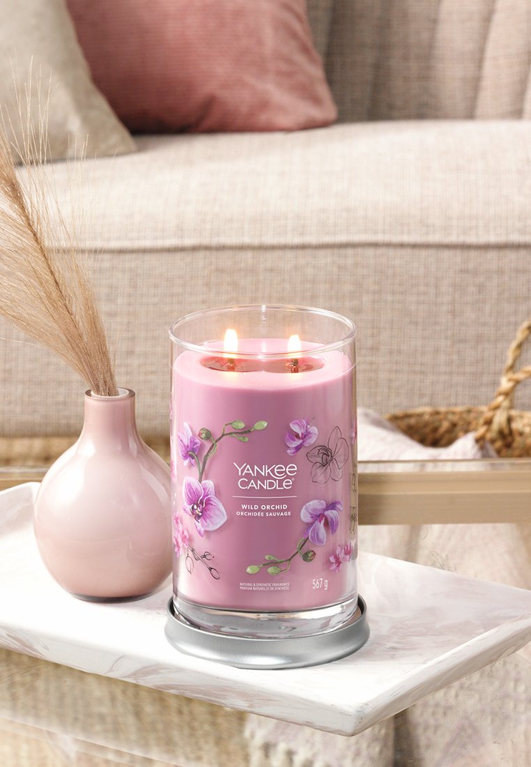 Yankee Candle mit pinkfarbener Wachsschicht und floralen Design, zwei Dochten, in einem klaren Glasbehälter auf einem runden silbernen Fuß.