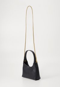 Sac à main en cuir noir avec un dessus arrondi, une chaîne dorée et une poignée découpée. Texture lisse avec un minimum de coutures et sans logos.