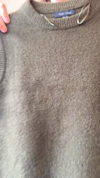 Grå stickad tröja med rund halsringning, som har en mjuk textur och subtila färgvariationer. Etiketten säger "NEW LOOK." Inga synliga mönster.