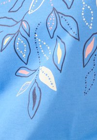 Tejido azul con un patrón de hojas contorneadas llenas de puntos y formas en pasteles rosa, amarillo y blanco.
