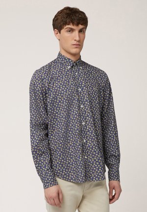 Langarmshirt in marineblauw met een gele bloemenpatroon. Heeft een button-down kraag en knopen aan de voorkant. Zachte stoftextuur.