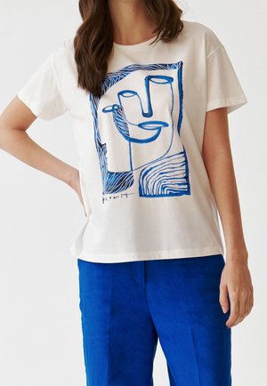 Biała bawełniana koszulka z niebieskim abstrakcyjnym rysunkiem linii przedstawiającym dłonie i ptaka, o luźnym kroju i krótkich rękawach.