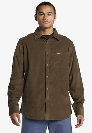 Bruin corduroy shirt met een button-down kraag, voorzak en een subtiele logo-detail. Lange mouwen, textuurstof en een relaxte pasvorm.