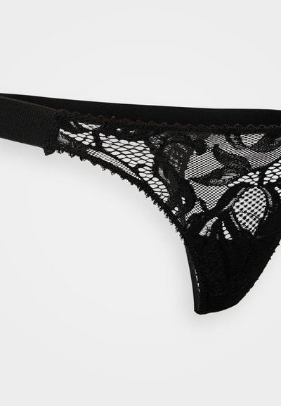 Fekete csipke tangaféle áttetsző hálóval, virágmintákkal és hullámos szegéllyel. Kényelmet biztosító sima elasztikus derékpánttal.