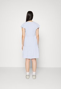 Vestido de algodão azul claro com mangas curtas com volantes e um design em camadas. A parte de trás tem um decote arredondado e fica acima dos joelhos.