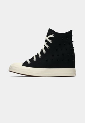 Black high-top sneaker with white laces and sole, featuring small black spikes on the side and back, against a plain background.