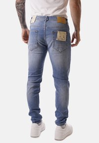 Jeans in denim blu chiaro, con una vestibilità slim, design a cinque tasche e etichette visibili sul retro, con una finitura testurizzata.